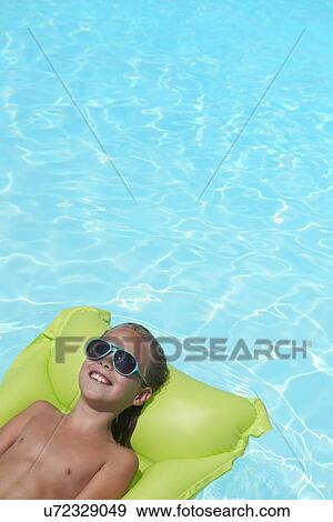 Boy lying on inflatable mattress in swimming pool View Large Photo Image Stock Photo - Boy lying on inflatable mattress in swimming pool. Fotosearch