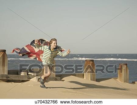 Boy running with union jack flag at beach, Southwold, Suffolk, UK View Large Photo Image Stock Photograph - Boy running with union jack flag at beach, Southwold, Suffolk, UK. Fotosearch