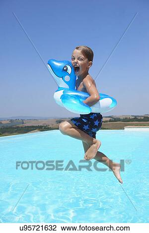 Boy wearing inflatable ring jumping into swimming pool View Large Photo Image Stock Image - Boy wearing inflatable ring jumping into swimming pool. Fotosearch