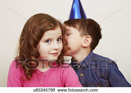 Boy wearing party hat whispering to girl View Large Photo Image Stock Photo - Boy wearing party hat whispering to girl. Fotosearch