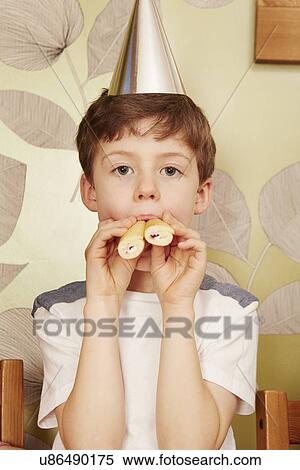 Boy wearing party hat with party food in mouth View Large Photo Image Stock Photography - Boy wearing party hat with party food in mouth. Fotosearch