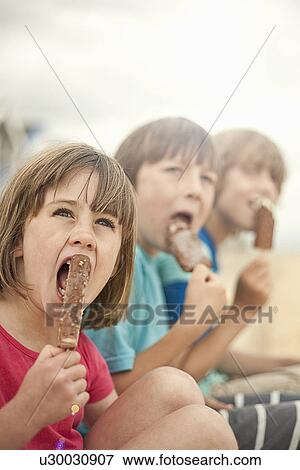 Brothers and sister enjoying ice lollies, Southwold, Suffolk, UK View Large Photo Image Stock Photo - Brothers and sister enjoying ice lollies, Southwold, Suffolk, UK. Fotosearch