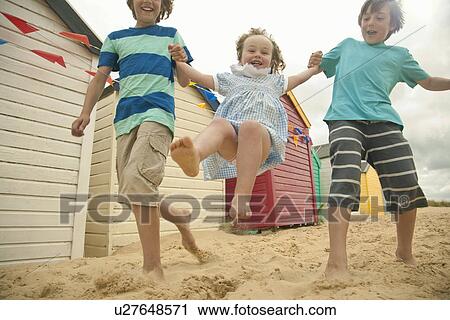 Brothers swinging toddler sister running, Southwold, Suffolk, UK View Large Photo Image Stock Image - Brothers swinging toddler sister running, Southwold, Suffolk, UK. Fotosearch