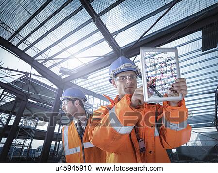 Builders working on plan details using digital tablet View Large Photo Image Stock Image - Builders working on plan details using digital tablet. Fotosearch
