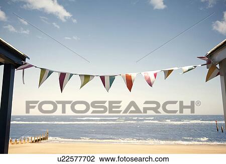 Stock Image - Bunting between beach huts, Southwold, Suffolk, UK. Fotosearch