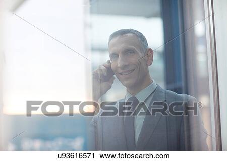 Stock Image - Businessman chatting on smartphone. Fotosearch