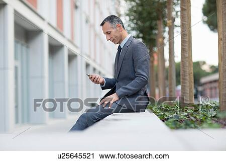 Businessman on lunch break texting on smartphone View Large Photo Image Stock Image - Businessman on lunch break texting on smartphone. Fotosearch