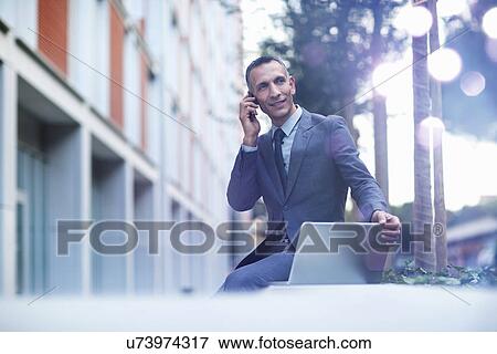 Businessman talking on smartphone and looking at glowing lights View Large Photo Image Stock Photo - Businessman talking on smartphone and looking at glowing lights. Fotosearch
