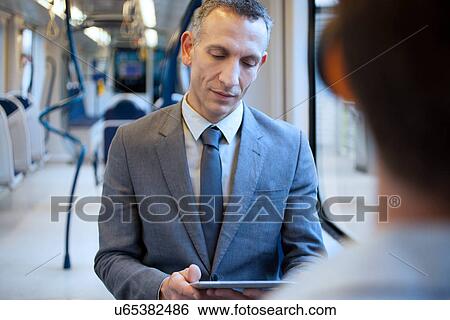 Stock Photograph - Businessman using digital tablet on train. Fotosearch