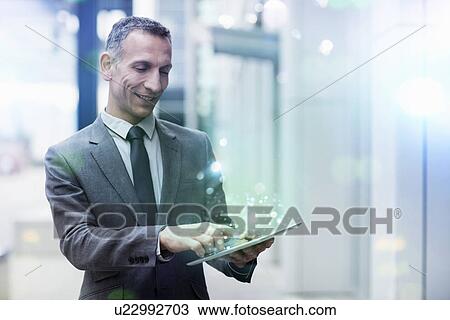 Businessman using digital tablet with glowing lights coming out of it View Large Photo Image Stock Image - Businessman using digital tablet with glowing lights coming out of it. Fotosearch