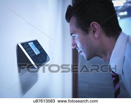 Stock Image - Businessman using face recognition system for office security. Fotosearch