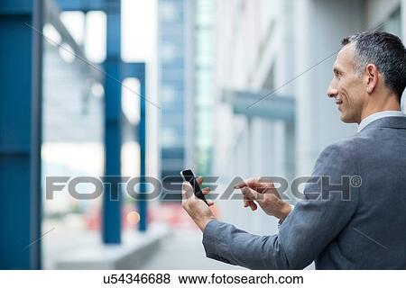 Stock Photo - Businessman using touchscreen on smartphone. Fotosearch