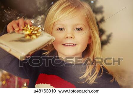 Stock Image - Child holding Christmas present. Fotosearch