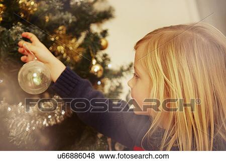 Stock Photo - Child looking at Christmas bauble. Fotosearch
