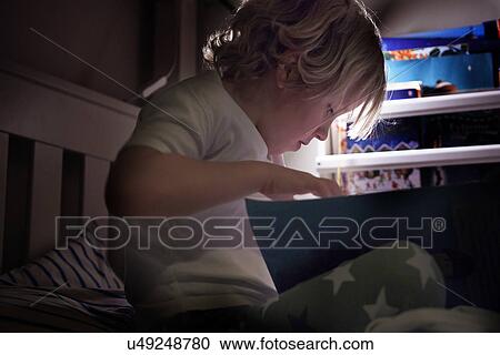 Stock Image - Child reading on bed. Fotosearch