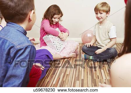 Stock Image - Children at party, girl holding birthday present. Fotosearch