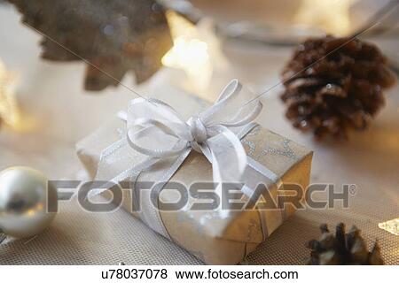 Stock Photo - Christmas table with gift, lights and fir cones. Fotosearch