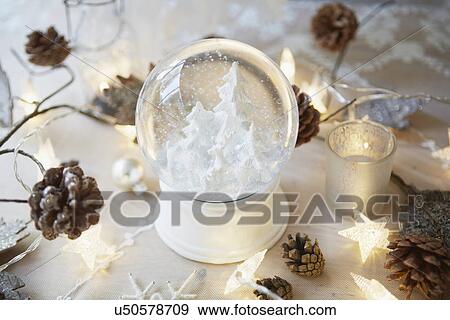 Stock Photo - Christmas table with snow globe and fir cones. Fotosearch
