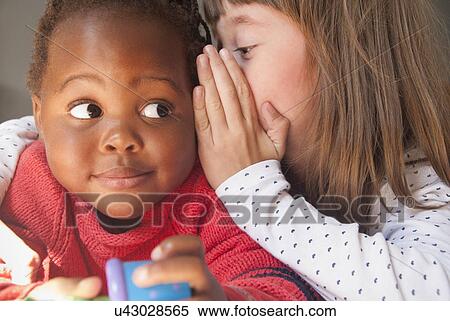 Close up of girl whispering to female toddler View Large Photo Image Stock Photography - Close up of girl whispering to female toddler. Fotosearch