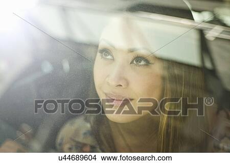 Picture - Close up of young woman looking out of car window. Fotosearch