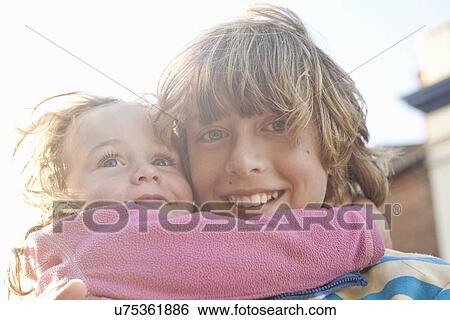 Stock Photograph - Close up portrait of boy and toddler sister hugging. Fotosearch