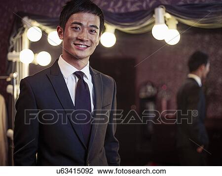 Stock Image - Confident young man in new suit in traditional tailors shop. Fotosearch