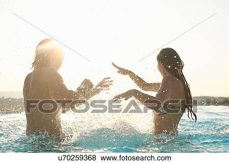 Couple having fun, splashing around in outdoor swimming pool View Large Photo Image Stock Photo - Couple having fun, splashing around in outdoor swimming pool. Fotosearch