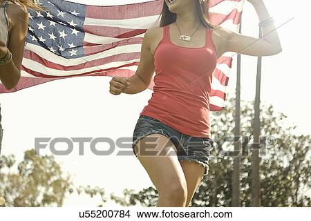 Cropped shot of two young woman running with american flag in park View Large Photo Image Picture - Cropped shot of two young woman running with american flag in park. Fotosearch