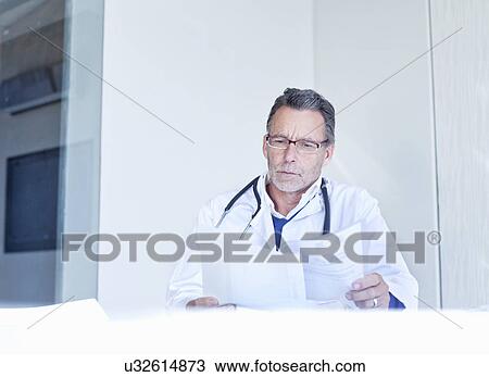 Stock Image -  Doctor looking at medical notes. Fotosearch