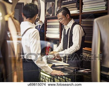 Picture - Father and son looking at fabric in family tailors shop. Fotosearch