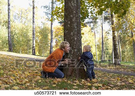 Stock Image - Father and son playing at bottom of tree. Fotosearch