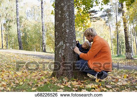 Stock Photograph - Father and son playing at bottom of tree. Fotosearch
