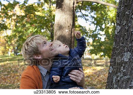 Stock Photography - Father and son playing at bottom of tree. Fotosearch
