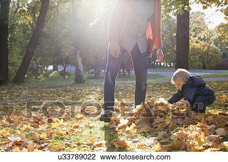 Stock Image - Father and son playing with autumn leaves. Fotosearch