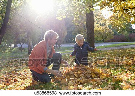 Father and son playing with autumn leaves View Large Photo Image Stock Photo - Father and son playing with autumn leaves. Fotosearch