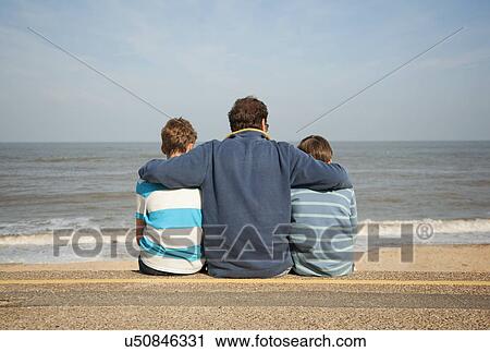 Stock Image - Father and sons on beach. Fotosearch