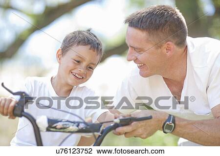 Father guiding son to cycle View Large Photo Image Stock Image - Father guiding son to cycle. Fotosearch
