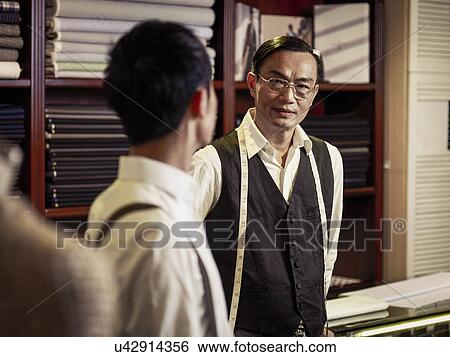 Father talking to son in family tailoring business View Large Photo Image Stock Photograph - Father talking to son in family tailoring business. Fotosearch