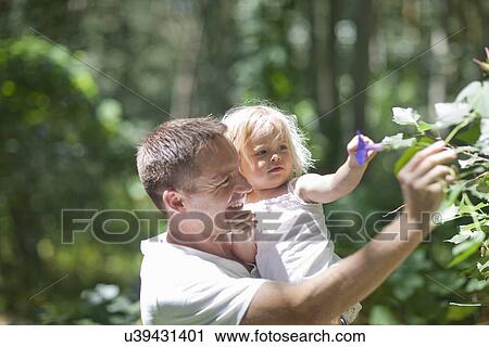 Father with baby girl plucking flowers in forest View Large Photo Image Stock Image - Father with baby girl plucking flowers in forest. Fotosearch