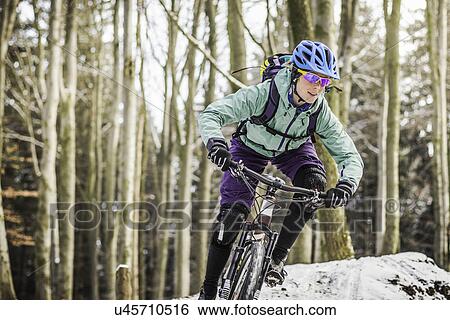 Female mountain biker riding through forest View Large Photo Image Stock Photograph - Female mountain biker riding through forest. Fotosearch
