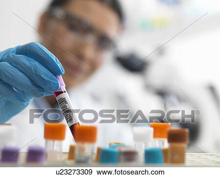 Stock Photo - Female scientist about to view a human sample under a microscope. Fotosearch