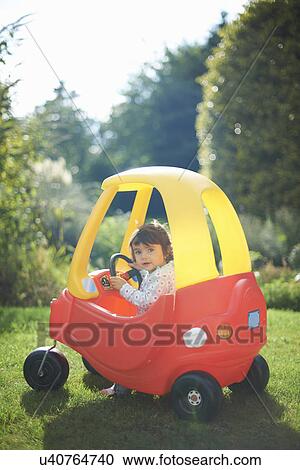 Female toddler playing in toy car in the garden View Large Photo Image Stock Image - Female toddler playing in toy car in the garden. Fotosearch