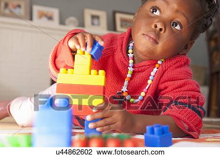 Stock Image - Female toddler playing with building blocks. Fotosearch