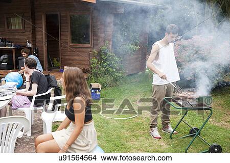 Picture - Four young adult friends in garden having barbecue. Fotosearch