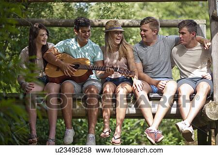 Stock Photo - Friends playing guitar and singing. Fotosearch