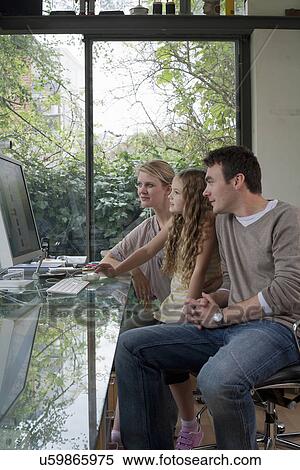 Stock Photography - Girl and parents at home using computer. Fotosearch