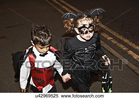 Stock Photography - Girl and toddler trick or treating at night. Fotosearch