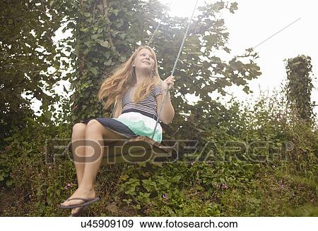 Stock Photo - Girl daydreaming on garden swing. Fotosearch