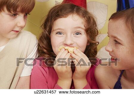 Girl eating party food, friends watching View Large Photo Image Stock Photo - Girl eating party food, friends watching. Fotosearch