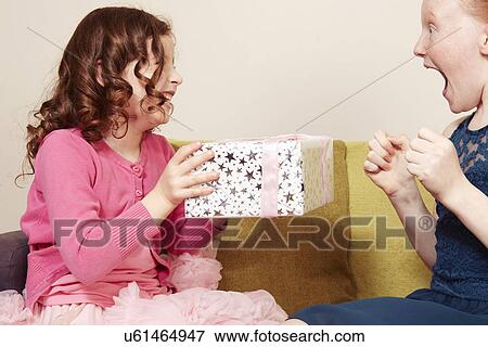 Girl giving friend birthday present View Large Photo Image Stock Photo - Girl giving friend birthday present. Fotosearch